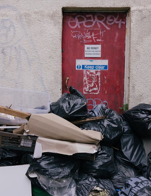 Two individuals are shown handling clear and black plastic rubbish bags. The person on the left, wearing jeans and checkerboard pattern shoes, is holding a transparent bag filled with mixed waste, inc